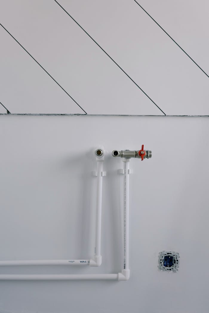 White wall with minimalist plumbing pipes and diagonal lines